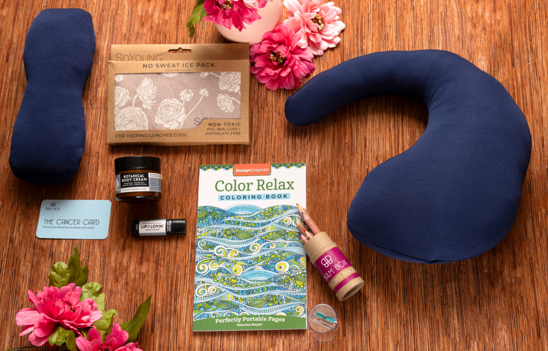 The Best Mastectomy Care Package: a navy neck pillow, no-sweat ice pack, small jars, gift card, coloring book, bottle, and lip balm—thoughtfully arranged with pink flowers for a comforting cancer or mastectomy gift box.