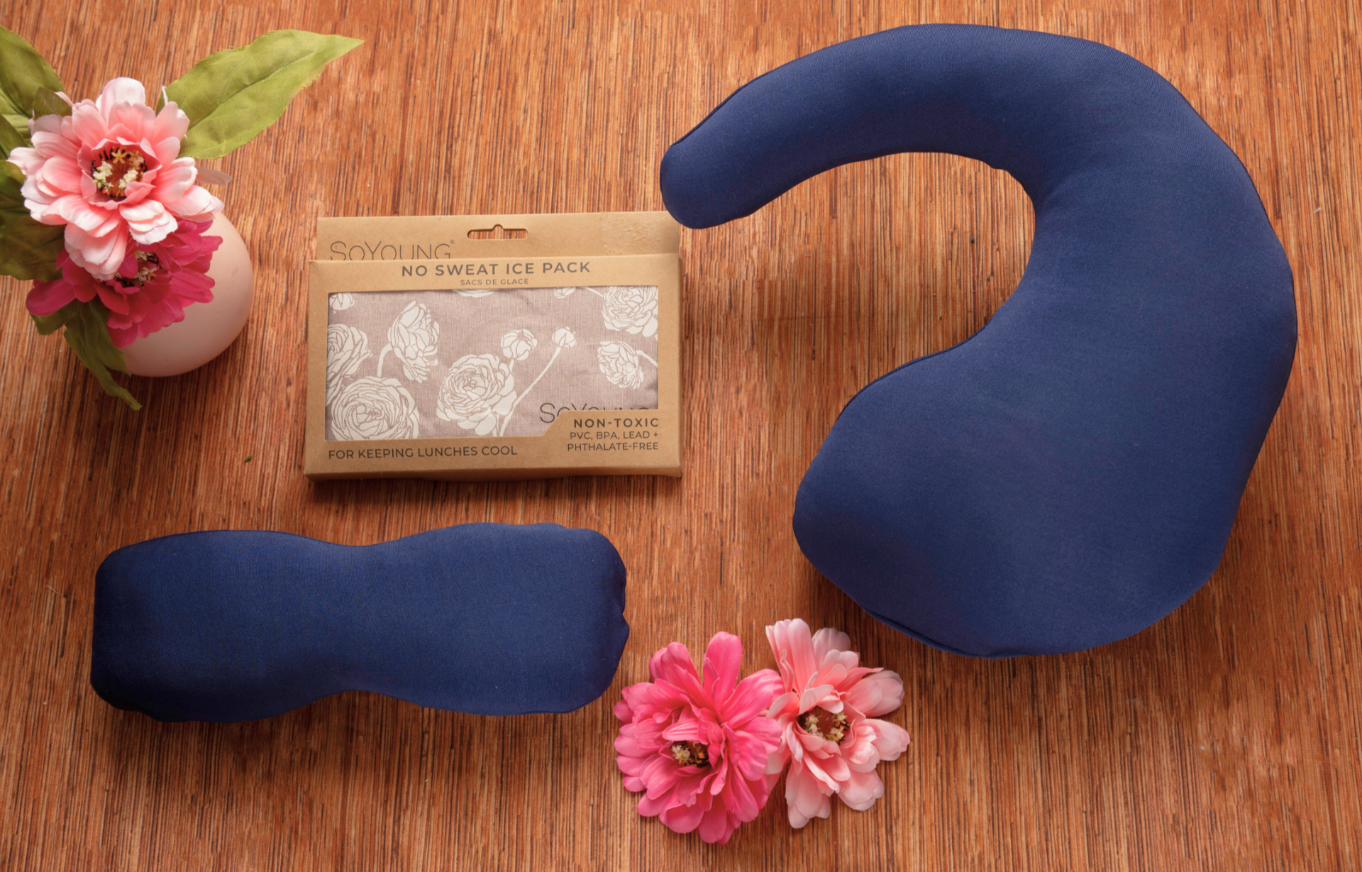 Three navy blue fabric ice packs in various shapes are displayed with pink flowers and a brown box labeled No Sweat Ice Pack—an ideal part of The Best Mastectomy Care Package.