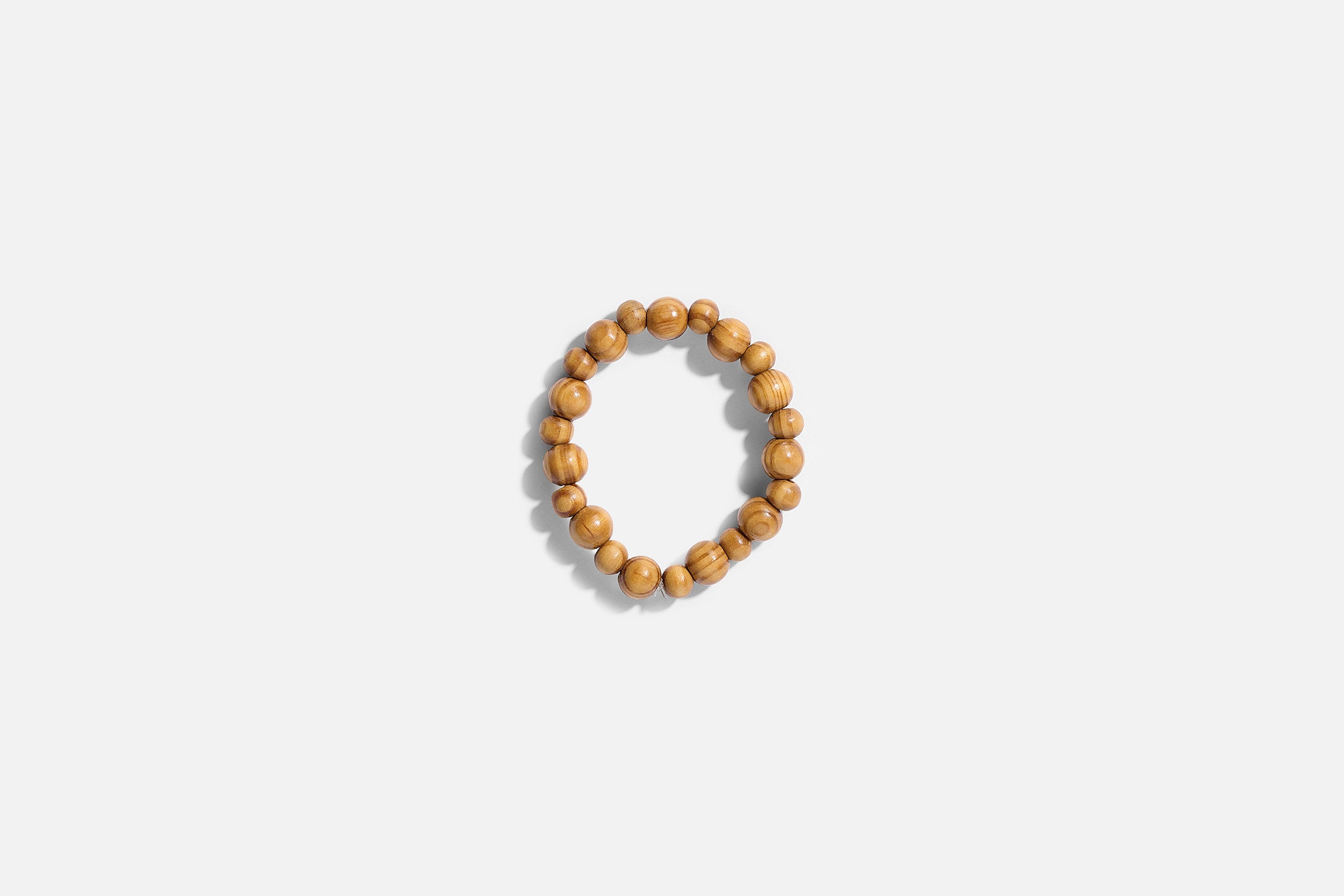 A circular beaded bracelet made of light brown wooden beads rests on a white background, ideal as a calming accessory during recovery or as part of The VIP Surgical Recovery Kit.