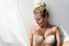 A woman in a bra by a window. Breast augmentation scars: what they look like, how long healing takes, and the pre- and post-op nutrition support that helps skin heal faster with Sulinu.