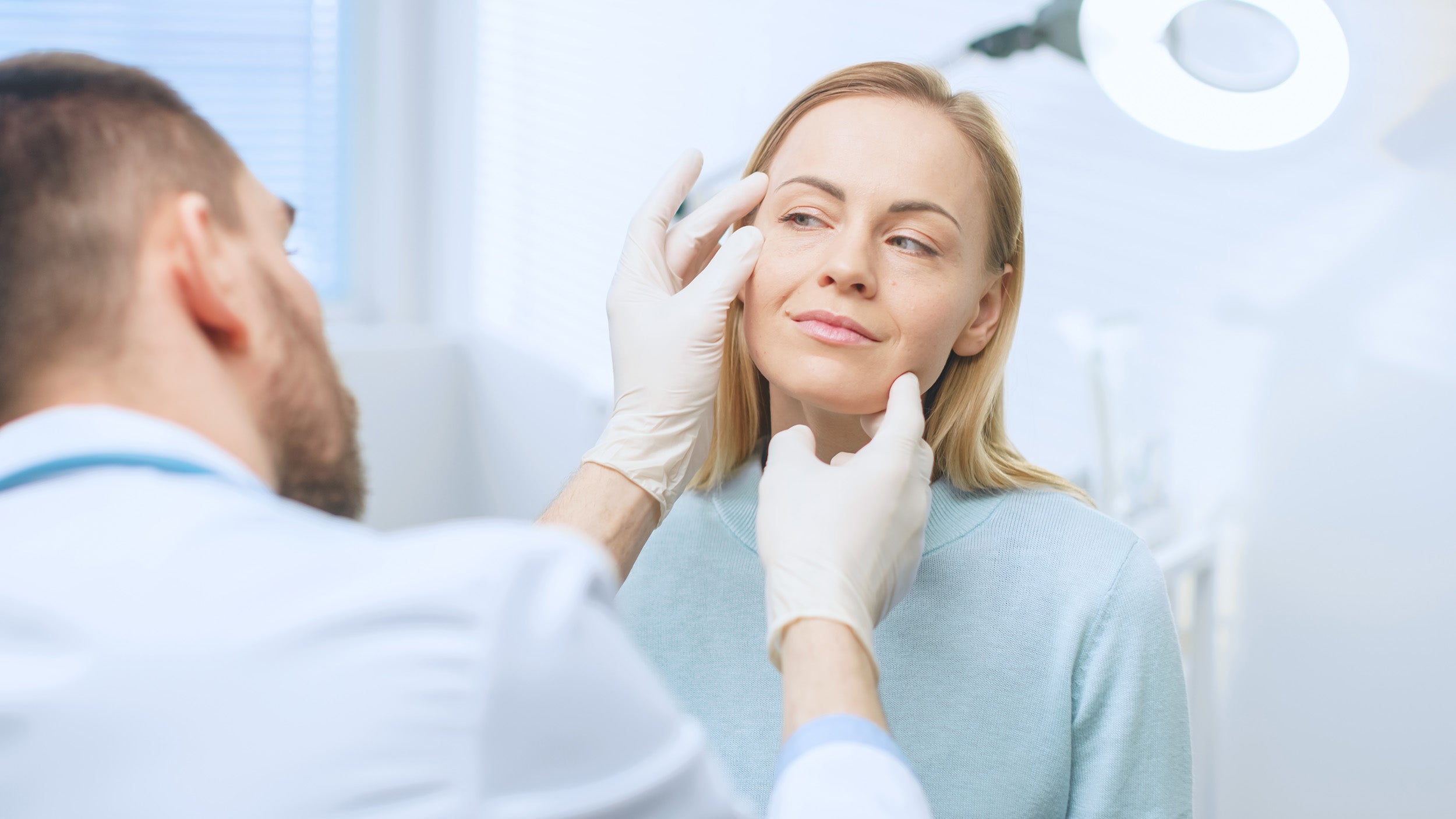 A woman consults with a surgeon. Deep plane facelift recovery takes 10-12 weeks for final results but delivers natural outcomes lasting 10-15 years. Learn what makes it different in our complete guide.