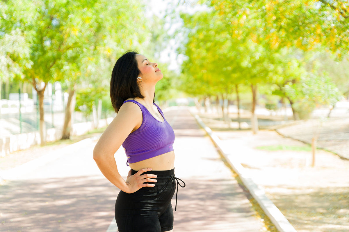 A woman takes a deep breath out on a walk. How long do breast reconstruction scars take to heal? Read our complete guide to learn more.