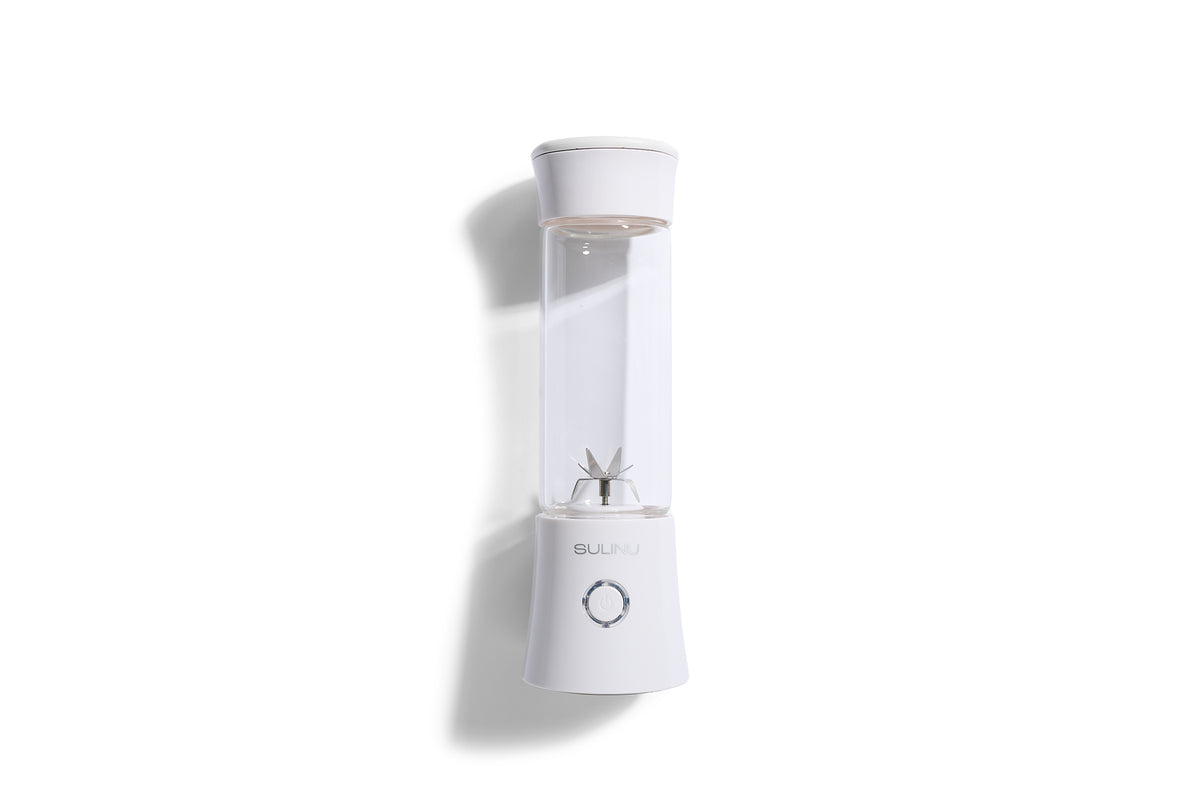 A Personal Blender in white with a clear cylindrical container, featuring a metal blade inside and a single power button on the base, is shown against a white background—ideal as a portable smoothie blender for your daily routines.