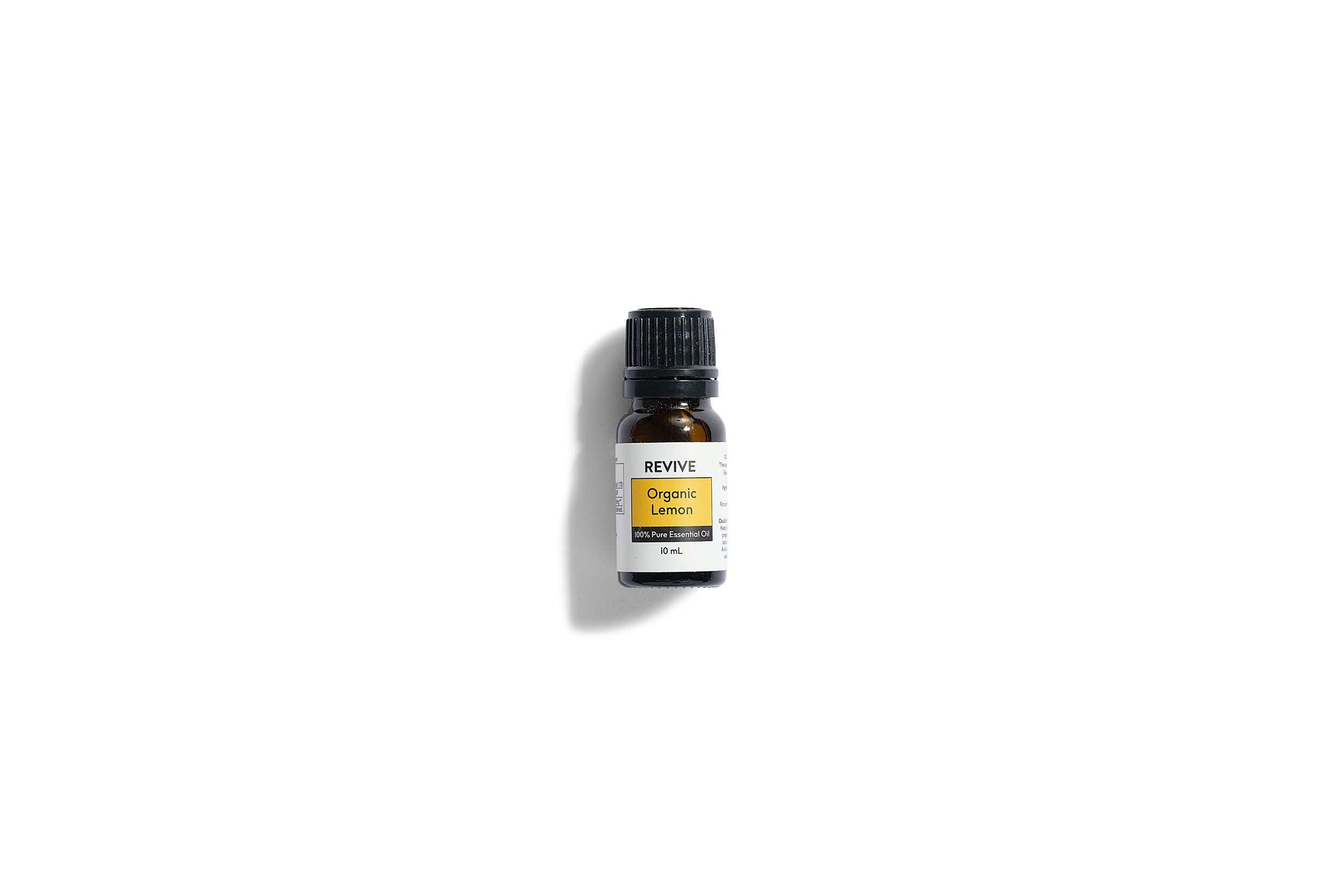 A small dark glass bottle labeled REVIVE Organic Lemon Essential Oil, 10 mL, sits on a white background—ideal for including in The VIP Surgical Recovery Kit to support your cosmetic surgery recovery.